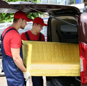 Günstig umziehen in Weinheim: Umzugshelfer laden ein gelbes Sofa in einen Transporter