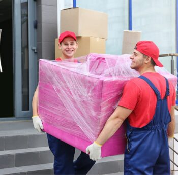 Zwei Umzugshelfer tragen ein in Folie gepacktes Möbelstück – Umzug in Weinheim