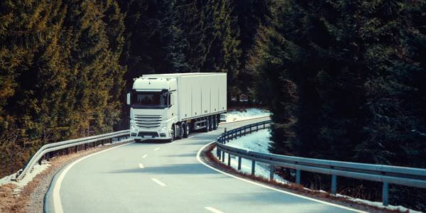 Klaviertransport Weinheim: Lkw fährt auf einer kurvigen Straße durch den Wald