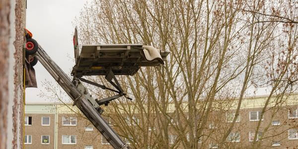 Möbellift zwischen kahlen Bäumen vor einem Gebäude – Möbellift in Weinheim