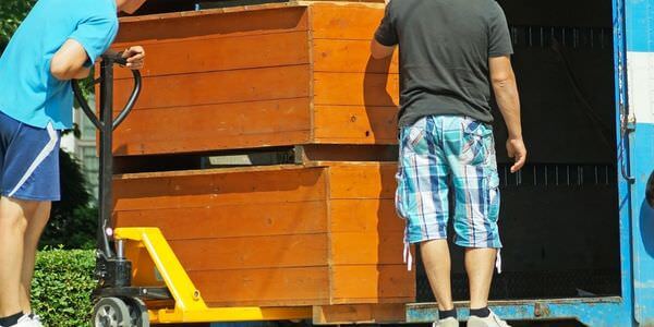 Möbellift Weinheim: Zwei Helfer tragen einen Holzschrank aus einem Lkw